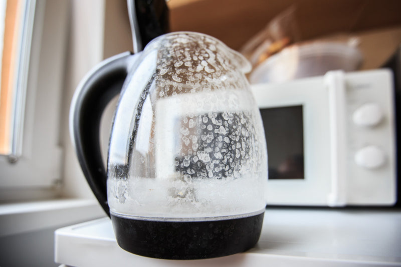 A glass kettle furred up with limescale